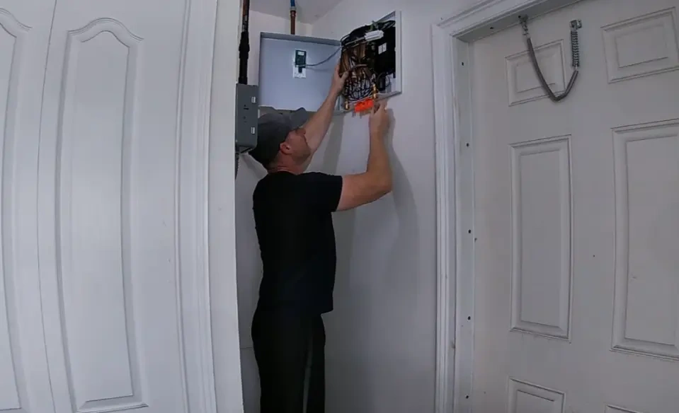 Technician connecting descaling equipment to tankless water heater service valves in Tustin California